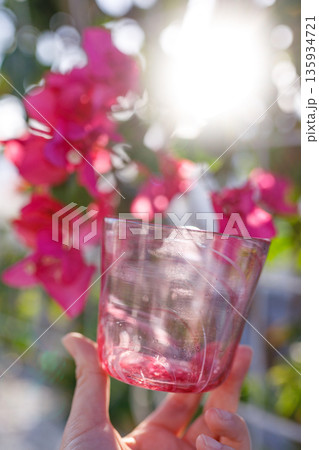 ブーゲンビリアの花と手に持つ琉球ガラスのグラス 135934721
