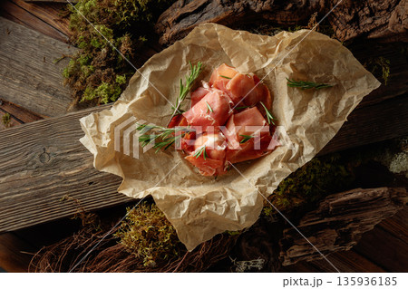 Prosciutto slices with rosemary wrapped in paper. Prosciutto slices with rosemary wrapped in paper. 135936185