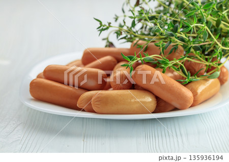 Boiled sausages with thyme on a white wooden table. Boiled sausages with thyme on a white wooden table. 135936194