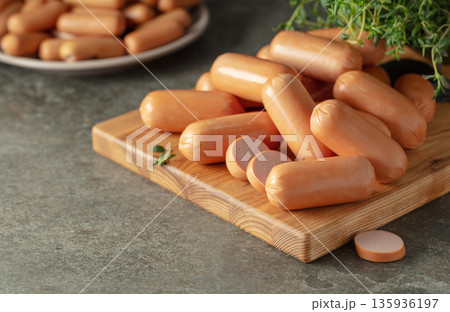 Small boiled sausages with thyme on a cutting board. 135936197
