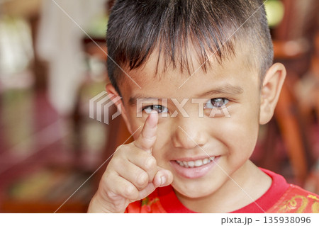 Portrait of a cute Asian little boy show one finger to camera with a blurry face 135938096