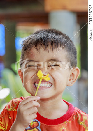 Close up cute portrait of Asian little boy holding and smell yellow flower in the garden 135938708