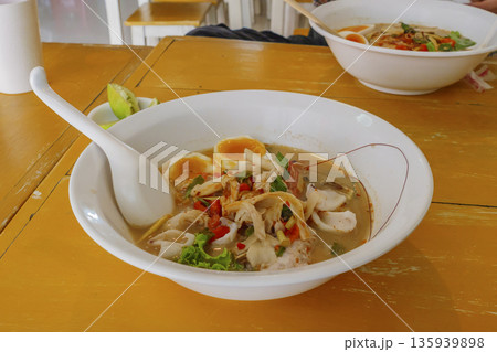 Spicy lemongrass flavored flat noodles with seafood in soup,  Thai traditional food 135939898