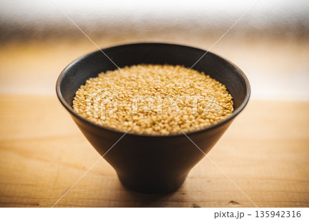 お茶碗に盛った玄米と木目のテーブル お茶碗に盛った玄米と木目のテーブル 135942316