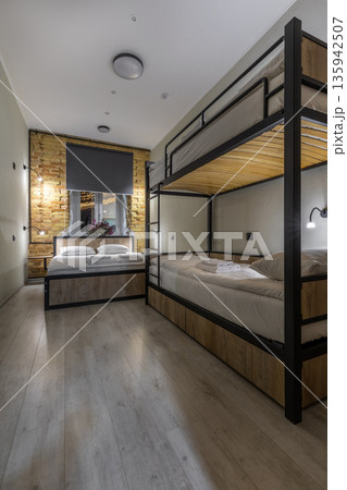 Modern hostel room interior with a double bed and bunk bed at night 135942507