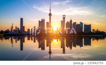 Urban cityscape panorama featuring a vibrant sunset and sunrise reflection over the river and lake water with a downtown building skyline and skyscraper view 135942733