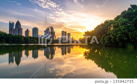 Urban cityscape panorama featuring a vibrant sunset and sunrise reflection over the river and lake water with a downtown building skyline and skyscraper view 135942735