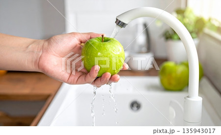 A woman practices good hygiene by washing her hands with soap and water at the bathroom sink faucet to stay clean and healthy at home 135943017