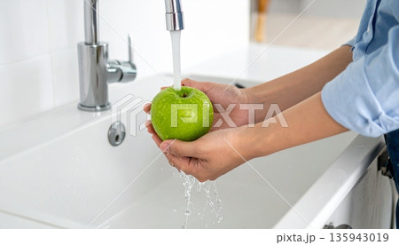 A woman practices good hygiene by washing her hands with soap and water at the bathroom sink faucet to stay clean and healthy at home 135943019
