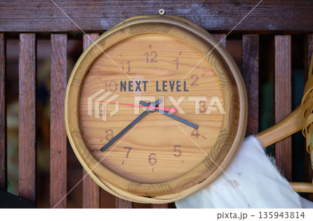 A beautifully crafted wooden clock hangs on a rustic wooden wall. The clock face displays the phrase next level in bold letters, highlighting a blend of simplicity and artistry A beautifully crafted wooden clock hangs on a rustic wooden wall. The clock face displays the phrase next level in bold letters, highlighting a blend of simplicity and artistry 135943814