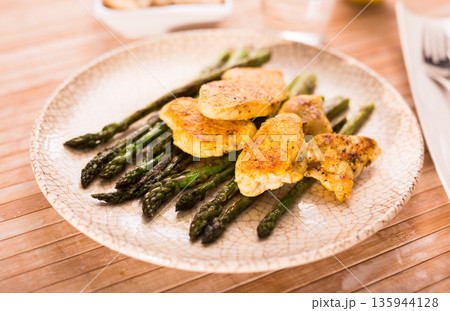 fried chicken breast pieces with asparagus on white plate 135944128
