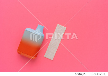 Disposable vape device with chewing gum strip on pink background, minimal flat lay Disposable vape device with chewing gum strip on pink background, minimal flat lay 135944204
