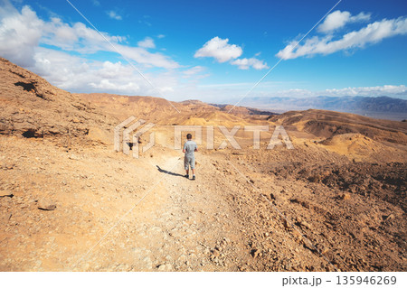 The young man is hiking in the desert on a sunny day. Eilat mountains in the Negev desert, Israel The young man is hiking in the desert on a sunny day. Eilat mountains in the Negev desert, Israel 135946269