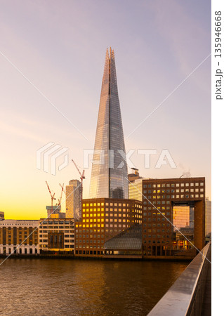 Sunlight shines on The Shard as it rises above the buildings of London. The city prepares for a new day with construction activity visible in the scene. Sunlight shines on The Shard as it rises above the buildings of London. The city prepares for a new day with construction activity visible in the scene. 135946668