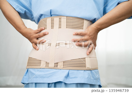 Asian lady patient wearing back pain support belt for orthopedic lumbar with walker. Asian lady patient wearing back pain support belt for orthopedic lumbar with walker. 135946739