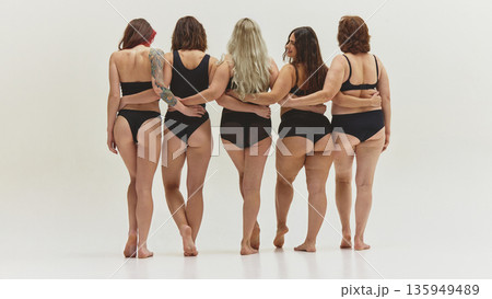 Women standing together back view in black underwear on light background. 135949489