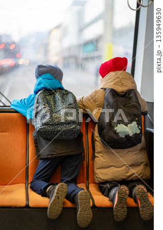 Two schoolchildren go to school in the back seat of a tram and look out the window. Two schoolchildren go to school in the back seat of a tram and look out the window. 135949630