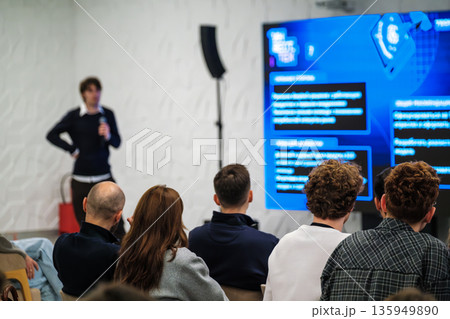 Presenter leads workshop in modern conference room with large blue digital display during a daytime session Presenter leads workshop in modern conference room with large blue digital display during a daytime session 135949890