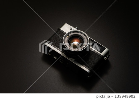 暗い背景にスポットライトが当たった古いフィルムカメラ 135949902