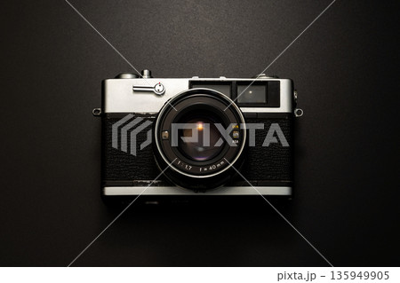 暗い背景にスポットライトが当たった古いフィルムカメラ 135949905