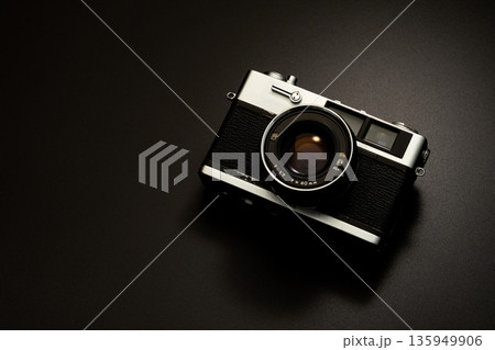 暗い背景にスポットライトが当たった古いフィルムカメラ 135949906