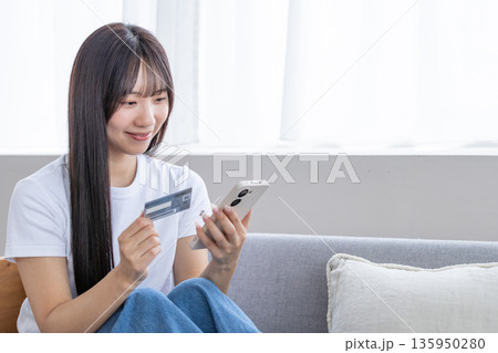 スマホとクレジットカードを持つ若い女性 135950280