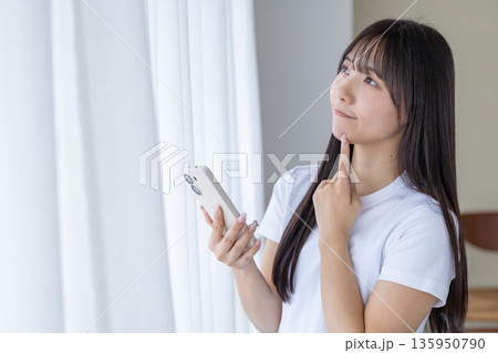 スマートフォンを持って考える若い女性 135950790