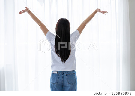 窓辺でストレッチをする若い女性 窓辺でストレッチをする若い女性 135950973