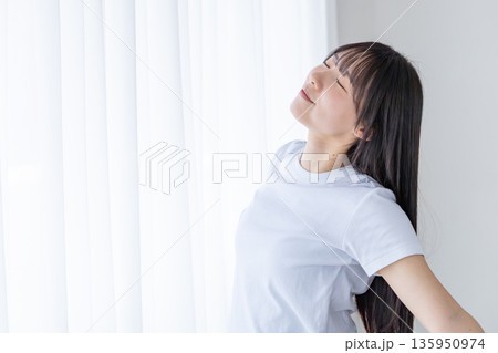 窓辺でストレッチをする若い女性 窓辺でストレッチをする若い女性 135950974
