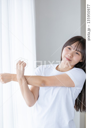 窓辺でストレッチをする若い女性 135950977