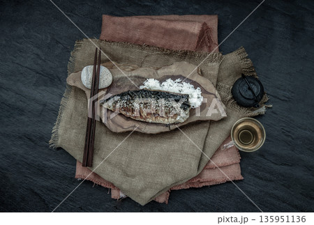 Japanese meal for dinner saba fish grilled on rice with teriyaki sauce on a wooden background served with hot tea. Japanese style. Japanese meal for dinner saba fish grilled on rice with teriyaki sauce on a wooden background served with hot tea. Japanese style. 135951136