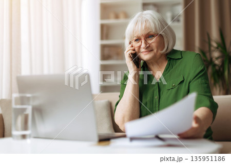 Senior woman smiling during phone call at home, elderly female enjoying communication 135951186