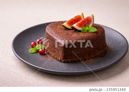Chocolate heart shaped dessert cake with figs on black plate for Valentines Day celebration Chocolate heart shaped dessert cake with figs on black plate for Valentines Day celebration 135951340