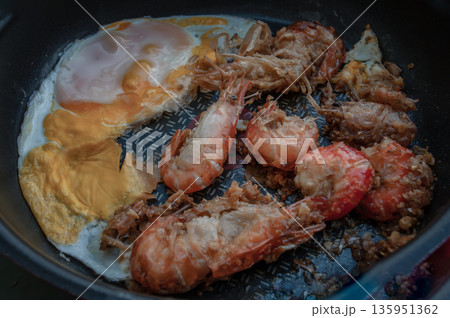 Tasty appetizing garlic Prawns, Shrimps on frying pan with Fried eggs in a frying. Top View with Copy space. Tasty appetizing garlic Prawns, Shrimps on frying pan with Fried eggs in a frying. Top View with Copy space. 135951362