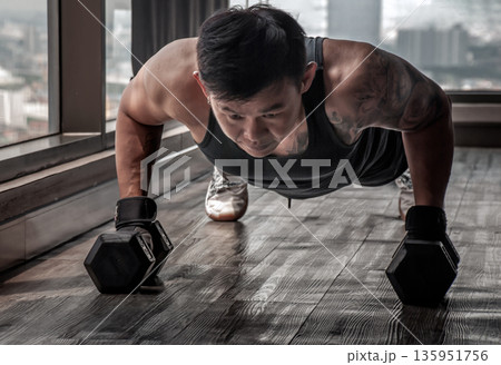 Handsome muscular man doing pushups on dumbbell in gym or fitness club. Healthy lifestyle bodybuilding. 135951756