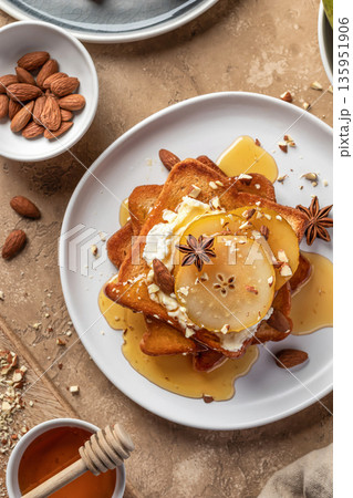 Yummy sweet toasts with caramelized pear, cream cheese, chopped nuts and honey syrup close up on brown textured background, top view Yummy sweet toasts with caramelized pear, cream cheese, chopped nuts and honey syrup close up on brown textured background, top view 135951906