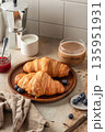 Delicious breakfast with croissants on wooden tray and coffee on white kitchen table background 135951931