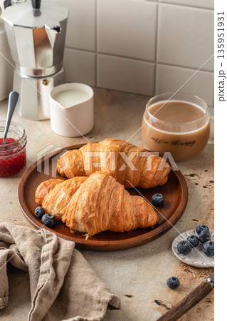 Delicious breakfast with croissants on wooden tray and coffee on white kitchen table background Delicious breakfast with croissants on wooden tray and coffee on white kitchen table background 135951931