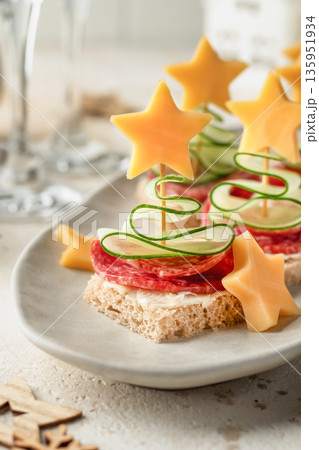 Cheese salami appetizers with cucumber on a plate. Delicious festive canapes for New Year party close up Cheese salami appetizers with cucumber on a plate. Delicious festive canapes for New Year party close up 135951934