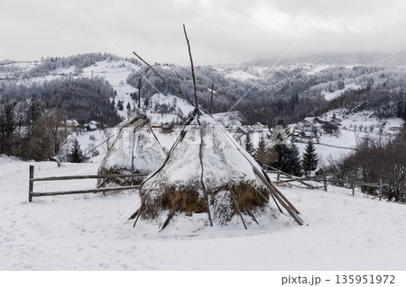 Traditional haystacks in snowy mountain village, Carpathian Mountains, Romania Traditional haystacks in snowy mountain village, Carpathian Mountains, Romania 135951972