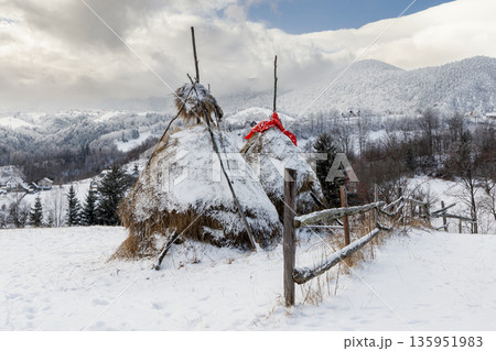 Traditional haystacks in snowy mountain village, Carpathian Mountains, Romania Traditional haystacks in snowy mountain village, Carpathian Mountains, Romania 135951983