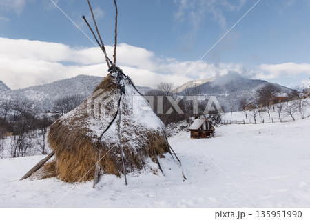 Traditional haystacks in snowy mountain village, Carpathian Mountains, Romania 135951990