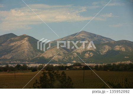 A sweeping mountain landscape in August 2025, with tiered, wooded hills under a clear summer sky. A sweeping mountain landscape in August 2025, with tiered, wooded hills under a clear summer sky. 135952092