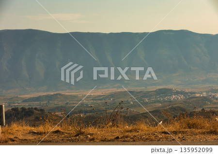A sweeping mountain landscape in August 2025, with tiered, wooded hills under a clear summer sky. A sweeping mountain landscape in August 2025, with tiered, wooded hills under a clear summer sky. 135952099