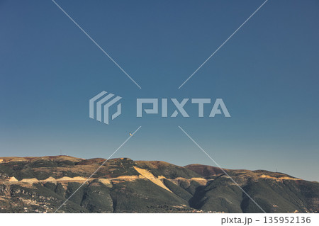 A sweeping mountain landscape in August 2025, with tiered, wooded hills under a clear summer sky. A sweeping mountain landscape in August 2025, with tiered, wooded hills under a clear summer sky. 135952136