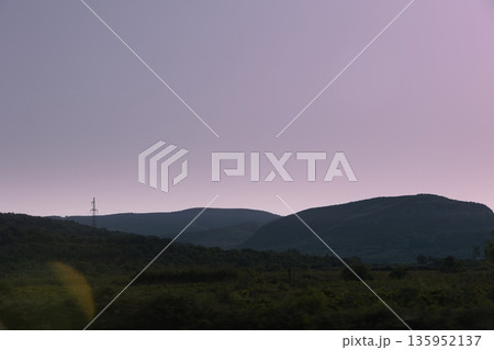 A sweeping mountain landscape in August 2025, with tiered, wooded hills under a clear summer sky. 135952137