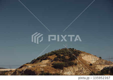 A sweeping mountain landscape in August 2025, with tiered, wooded hills under a clear summer sky. A sweeping mountain landscape in August 2025, with tiered, wooded hills under a clear summer sky. 135952167