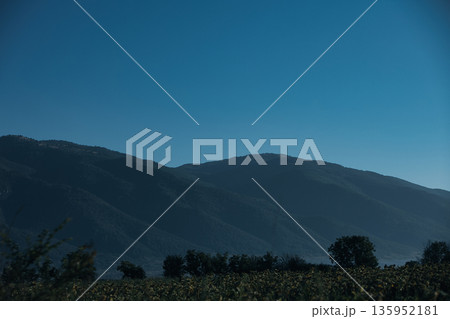 A sweeping mountain landscape in August 2025, with tiered, wooded hills under a clear summer sky. A sweeping mountain landscape in August 2025, with tiered, wooded hills under a clear summer sky. 135952181