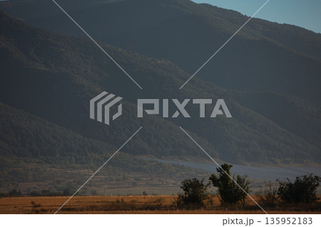 A sweeping mountain landscape in August 2025, with tiered, wooded hills under a clear summer sky. 135952183