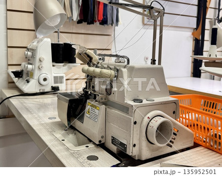 sewing workshop with a work area sewing machine filled with threads and working tools 135952501
